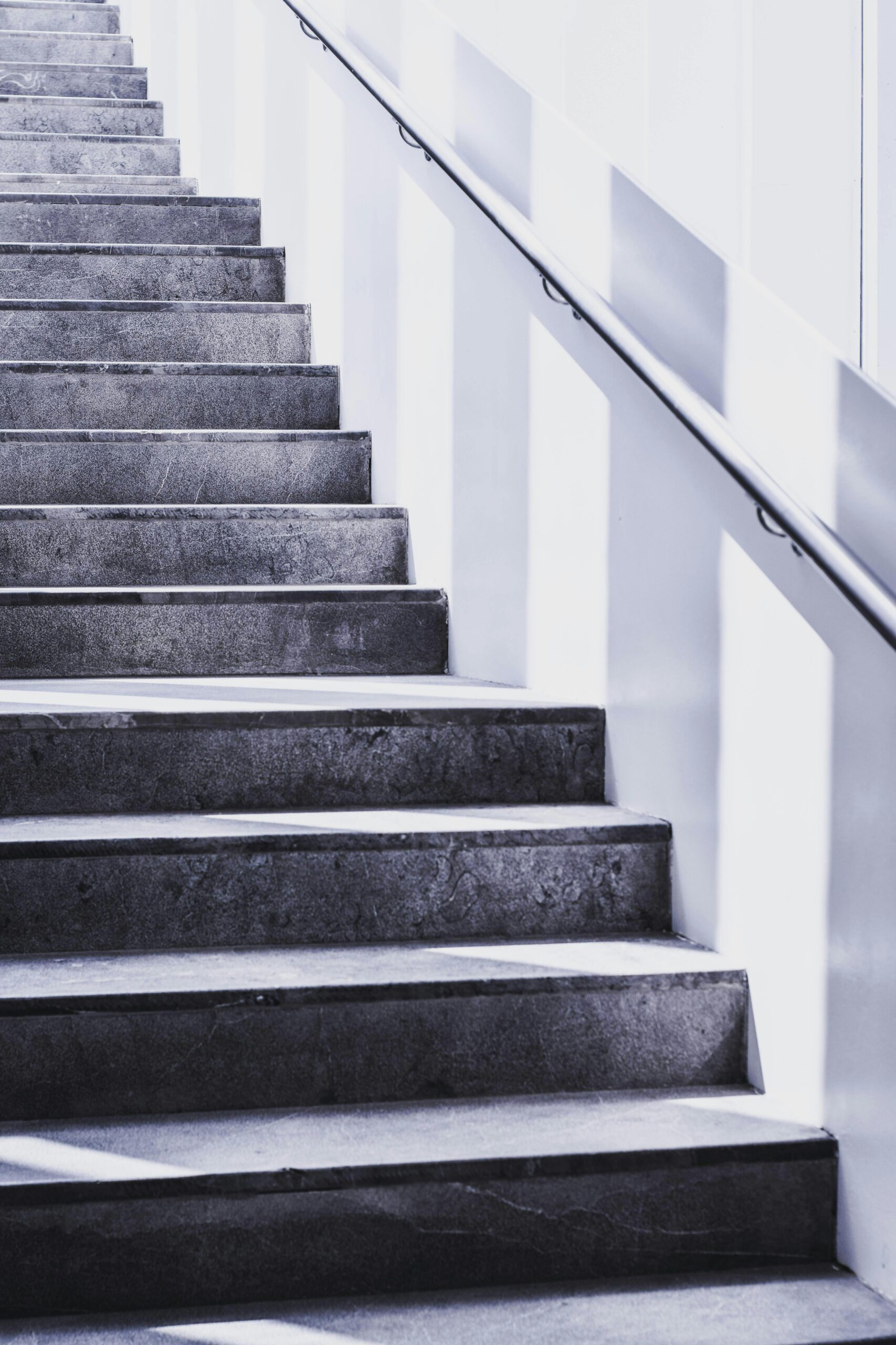 Concrete staircase with sunlight casting shadows, symbolizing consistent progress